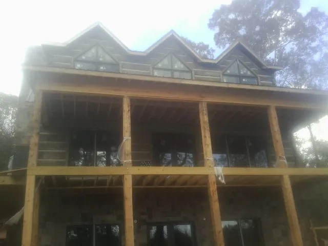 Dormers and porch framing on a large log home under construction — Roof Coating work by our crew in Manhattan