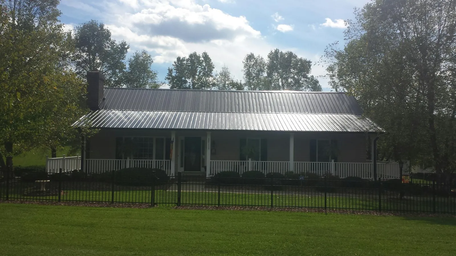 Gray metal roof on a brick ranch with a full width front porch — Gutter Guard Installation work by our crew in Manhattan